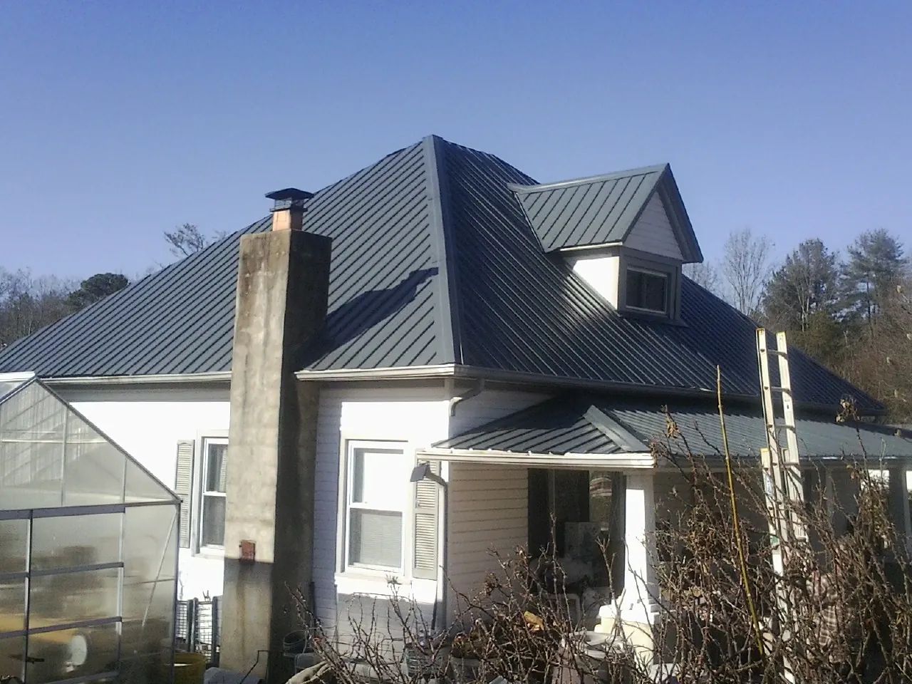 Dark blue standing seam metal roof on a white farmhouse with dormer — Slate & Tile Roof Repair by Roofing Brothers in Duanesburg