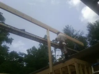 Carpenter setting a ridge beam over a new addition frame — Ice Dam Removal by Roofing Brothers in Duanesburg