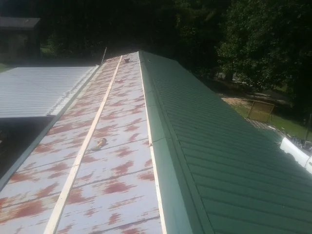 Old rusted panels beside newly installed green metal roofing — Wind Damage Roof Repair by Roofing Brothers in Duanesburg