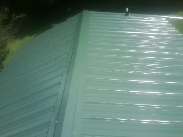 New green metal panels meeting at the ridge of a roof — Flat Roof Repair work by our crew in Duanesburg