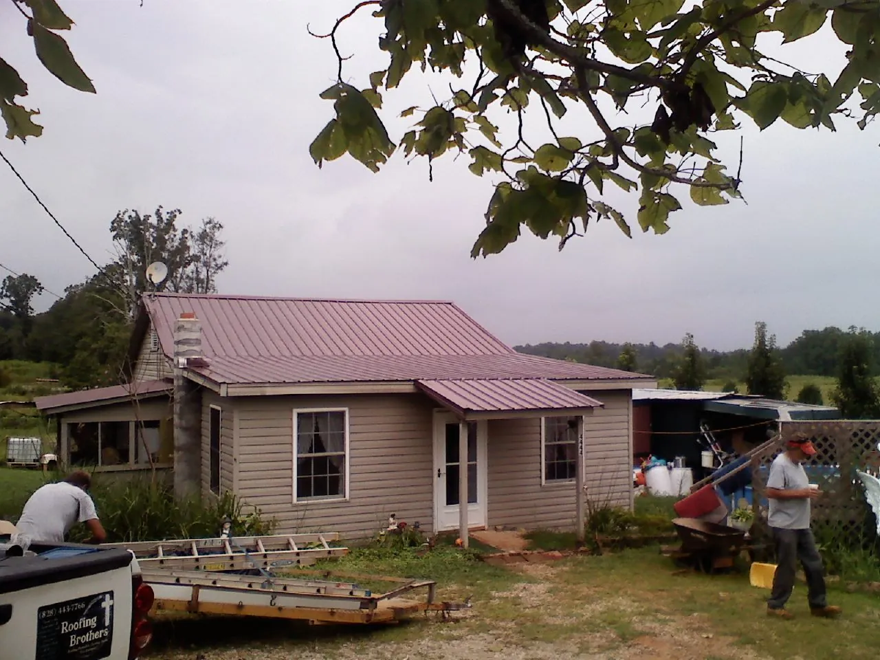 Crew finishing a mauve metal roof on a small farmhouse in Duanesburg