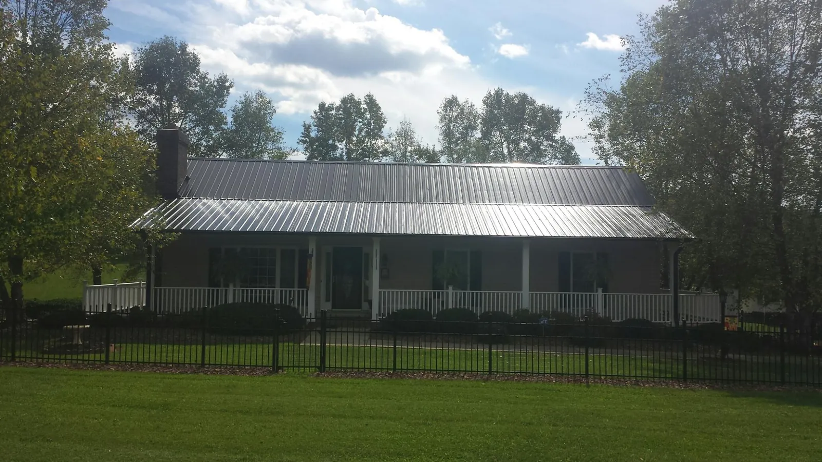 Gray metal roof on a brick ranch with a full width front porch — Gutter Guard Installation work by our crew in Duanesburg