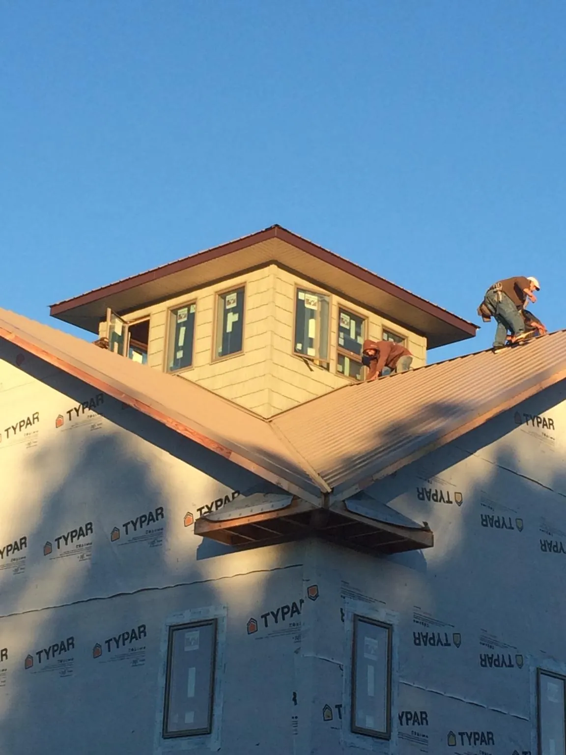 Roofers working around a rooftop cupola on a new metal roof at sunset — Roof Waterproofing in Duanesburg by Roofing Brothers